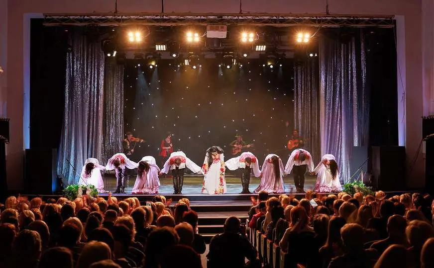 A collective of musicians, singers and dancers in gypsy costumes perform on stage.