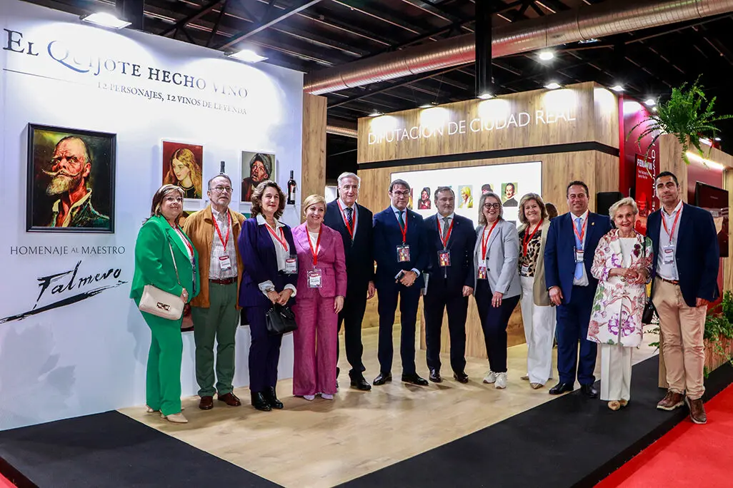 Posado de promotores y autoridades junto a uno de los grandes paneles de _El Quijote hecho vino_ en el stand de Diputaci&oacute;n