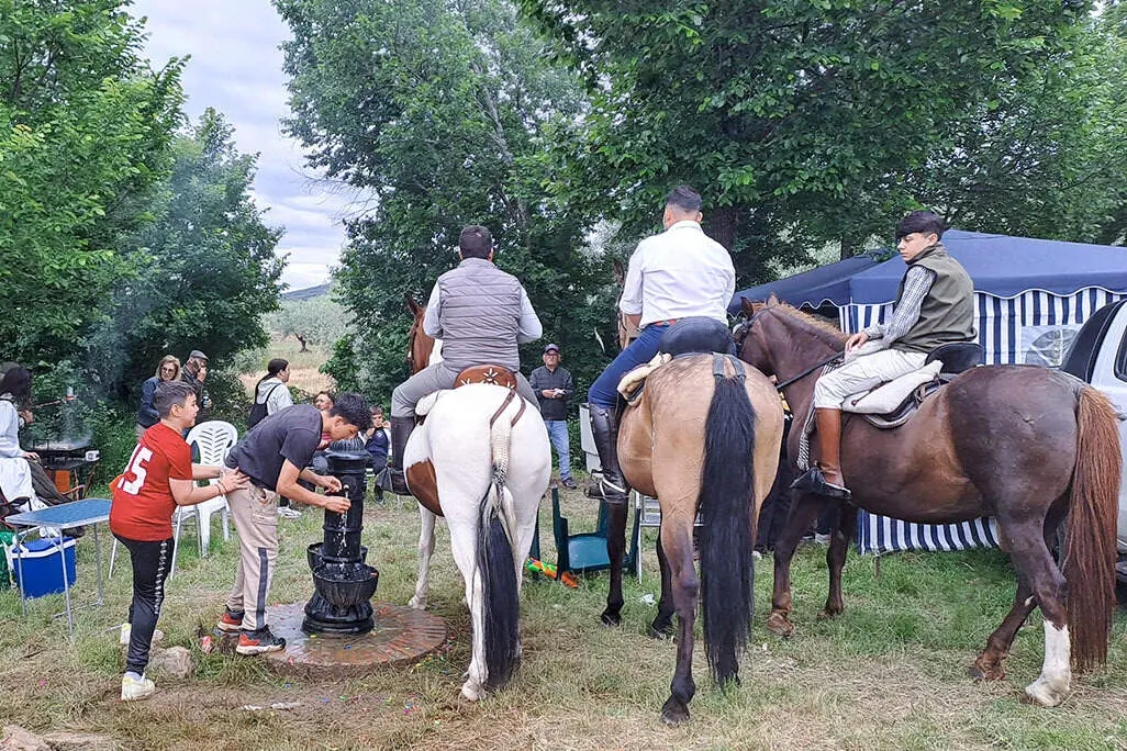 Un grupo de j&oacute;venes, a caballo y a pie, en torno a la ermita de san Isidro