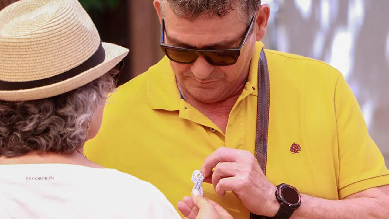 Un hombre recibe uno de los lazos azules tejidos para reinvidicar en este D&iacute;a Mundial del C&aacute;ncer de Pr&oacute;stata