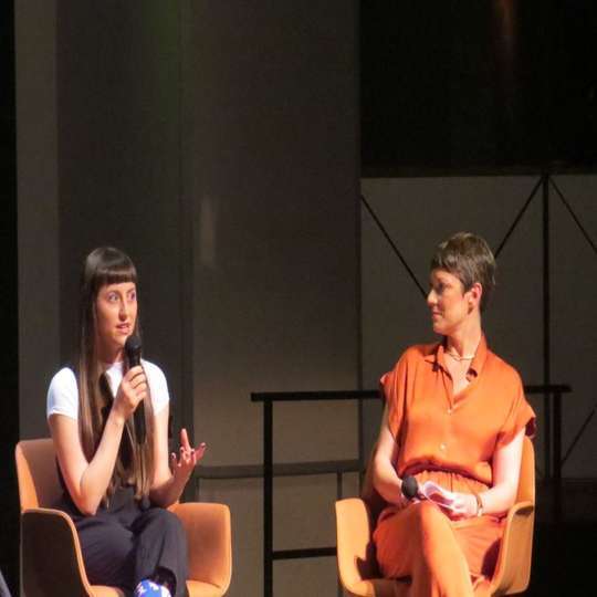 Laura Sansegundo, artista visual, con el micrófono,  y la directora de PHotoESPAÑA, María Santoyo