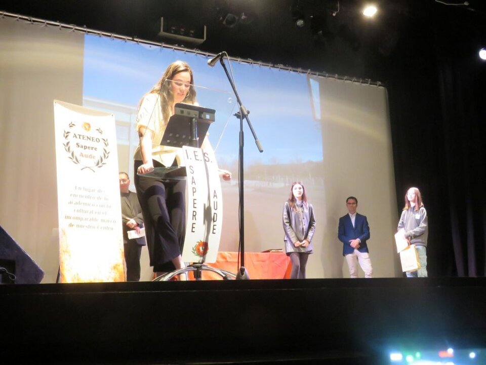 María Mazo invitó al escenario a la alumna Ángela González Juan, premio Literarios Atrevimientos 2025 con su escrito “Atrapado en sueños”. Le entregó el premio la alumna Miriam López López