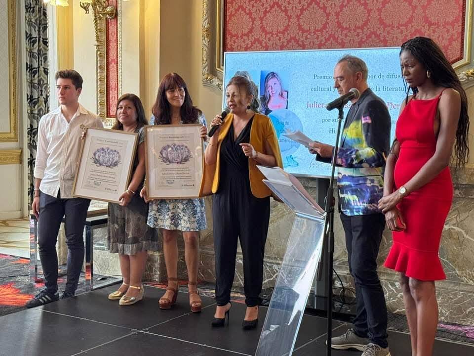 Julieta Deossa, con el micrófono y Rocío Hervias, con su galardón ,Premios a la mejor labor de difusión cultural y promoción de la literatura, por su «Ciclo de Literaturas Hispanoamericanas», entregados a Julieta Deossa por Marisol Esteban, escritora y a Rocio Hervias, por Alejandro Rodriguez Delgado, miembro de la familia Sial Pigmalión