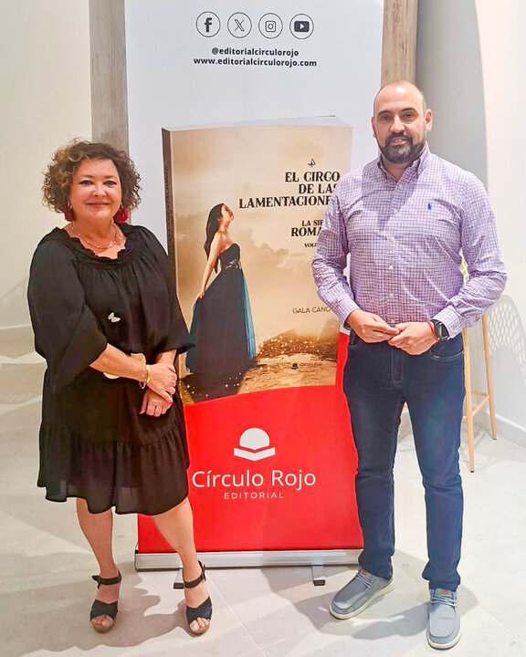Posado junto al cartelón que presenta la portada de _El circo de las lamentaciones_