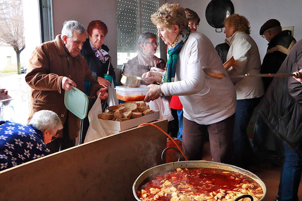 Vecinos, recibiendo en sus recipientes la comida de patatas y bacalao